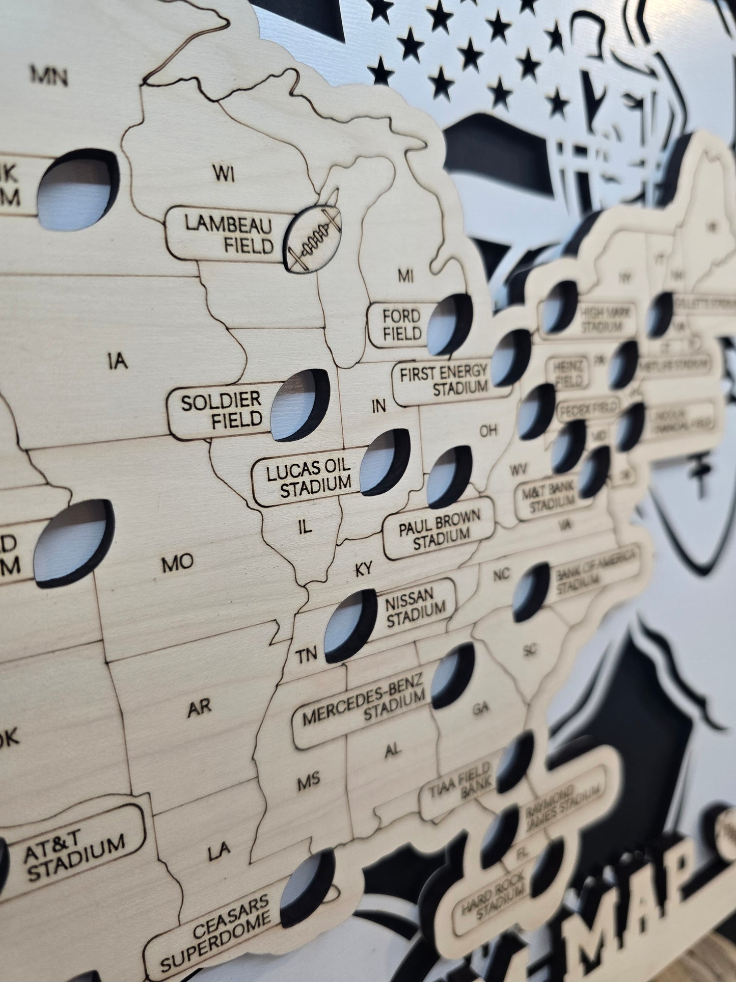 Close-up of the Stadium Series Football Map showing engraved stadium names like Lambeau Field, Ford Field, and Soldier Field with cut-out markers for each stadium