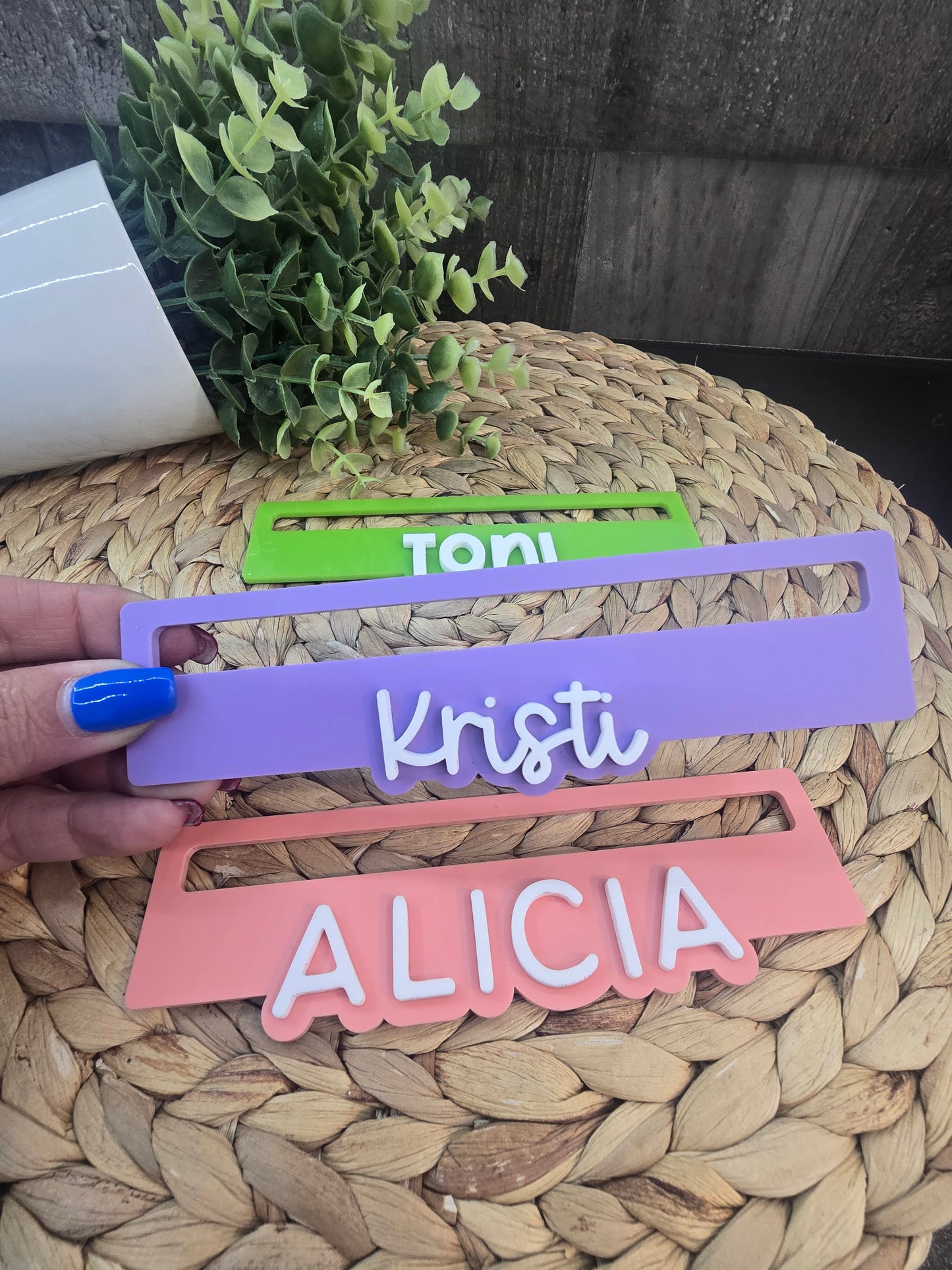 Close-up of three personalized Mahjong line readers in green, purple, and pink acrylic engraved with the names Toni, Kristi, and Alicia