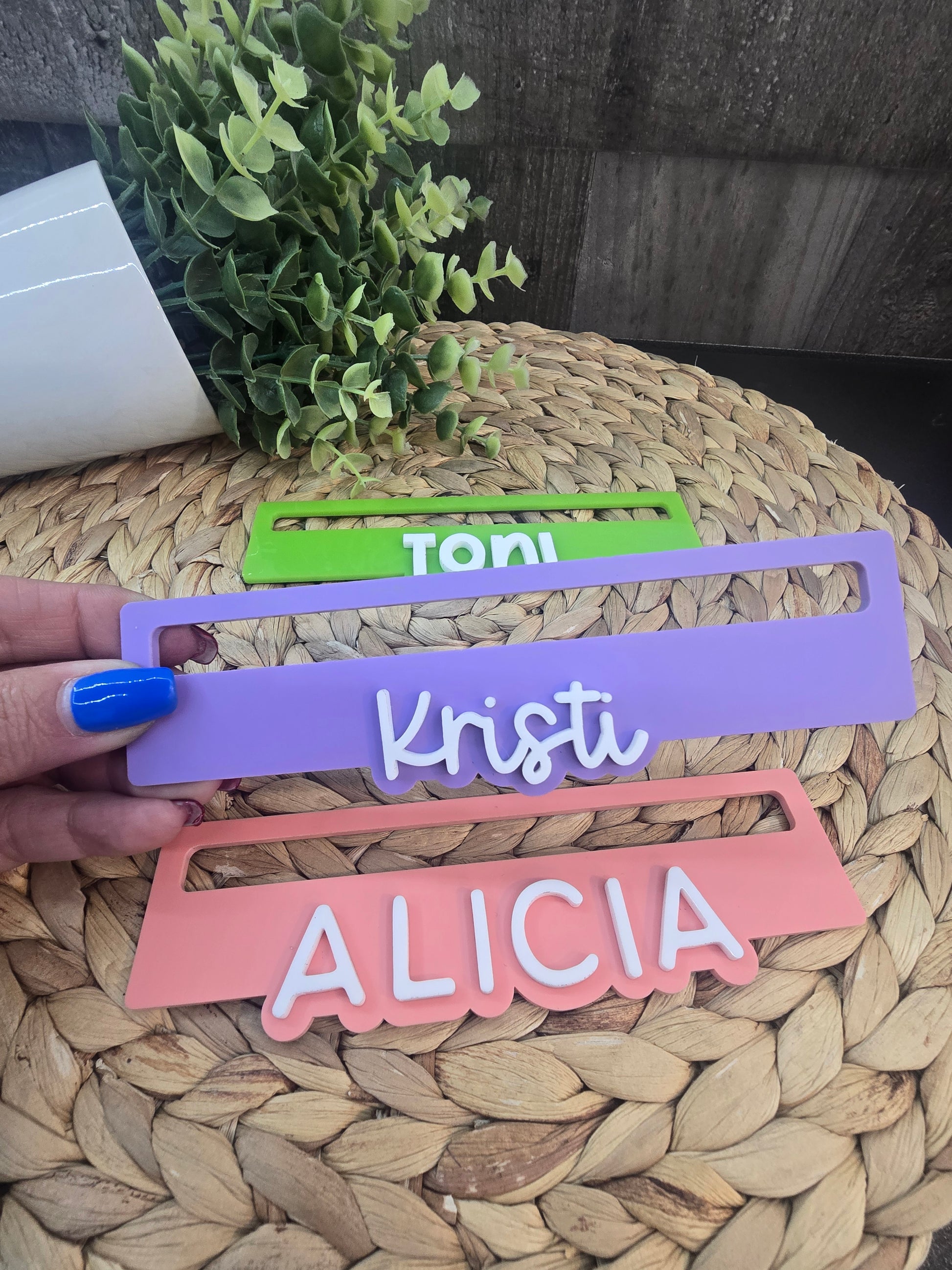 Close-up of three personalized Mahjong line readers in green, purple, and pink acrylic engraved with the names Toni, Kristi, and Alicia
